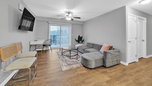 Un salon moderne avec un canapé d'angle gris, une table basse ronde et un banc en rotin.