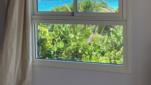 A window with a view of the ocean and greenery. - Villa Mahina, surfing and panoramic ocean views! (Le Moule)