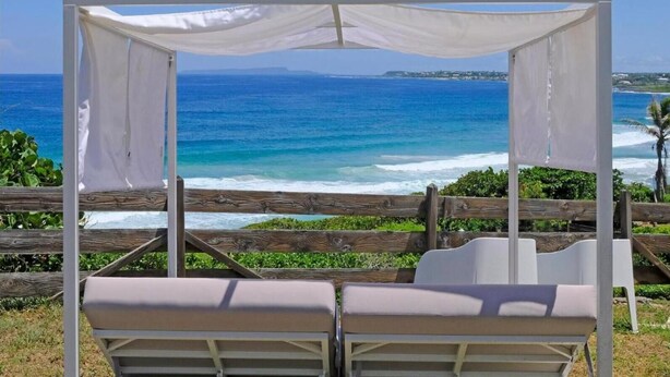 A beach view with a white canopy and two lounge chairs. - Villa Mahina, surfing and panoramic ocean views! (Le Moule)