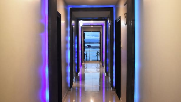 En modern hotellkorridor med ett reflekterande golv och blå belysning längs väggarna.