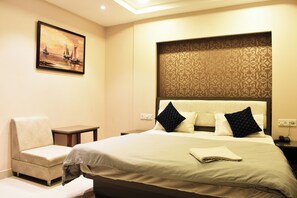 Ein Hotelzimmer mit Bett, Sessel, Nachttisch und einem Bild an der Wand.