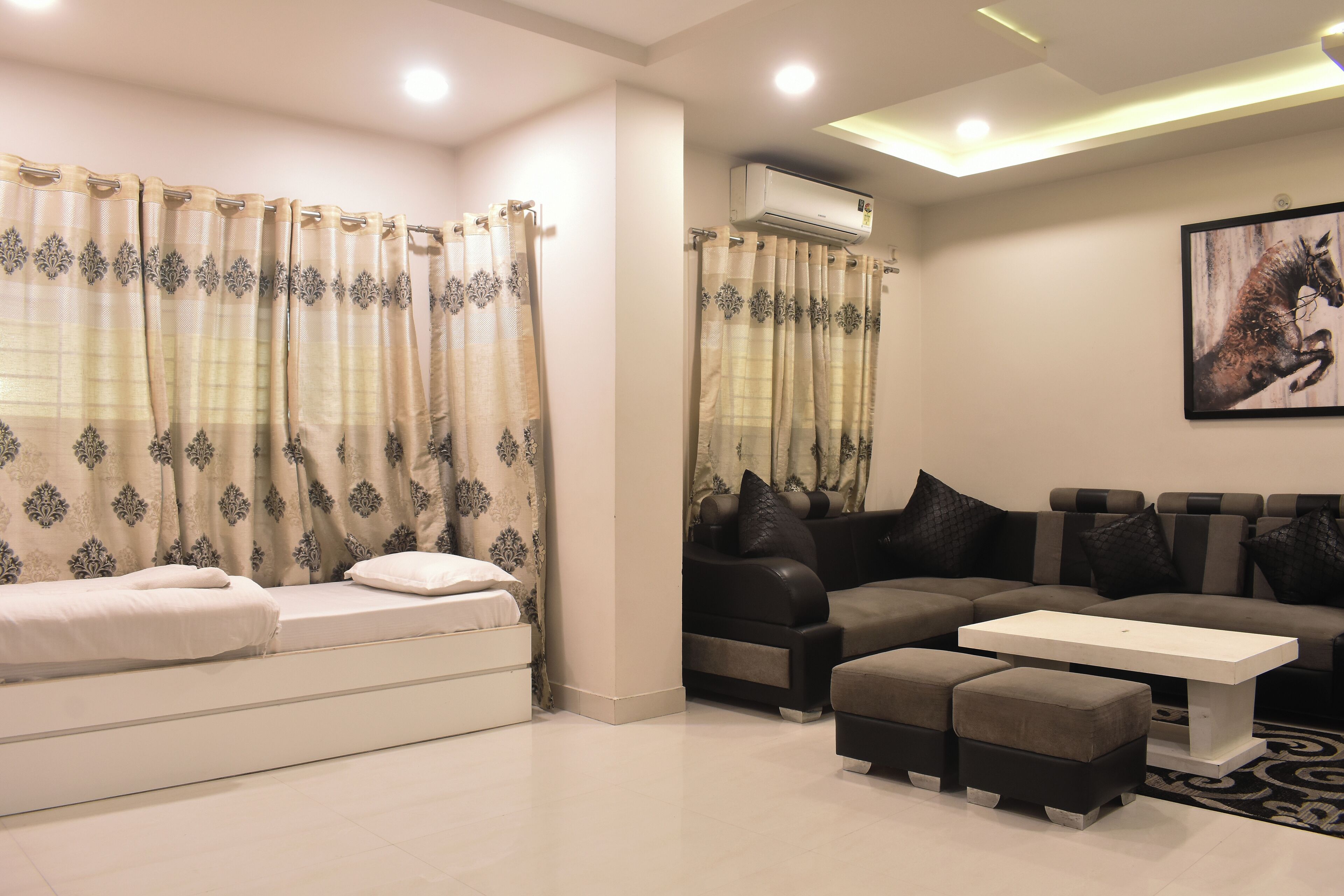 A modern living room with a sofa, ottomans, a coffee table, and a painting on the wall.