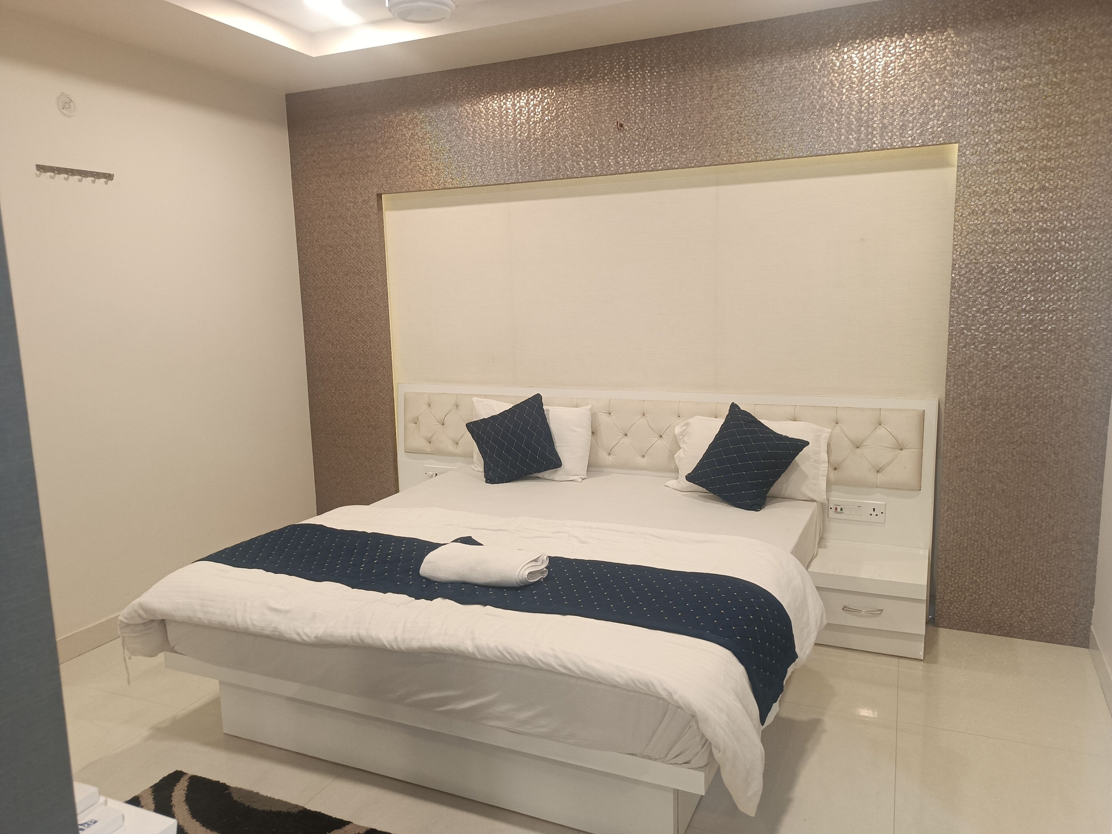 A neatly made bed with a white and blue bedspread, two pillows, and a folded towel.