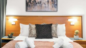 A hotel room with a wooden headboard, two bedside lamps, a cityscape painting, and a bed with white and pink bedding. - Urban Oasis Chic CBD Suite with WiFi - Walkable (Adelaide)