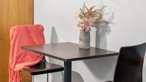 A dining area with a table, two chairs, a vase with flowers, and a painting on the wall. - Urban Oasis Chic CBD Suite with WiFi - Walkable (Adelaide)