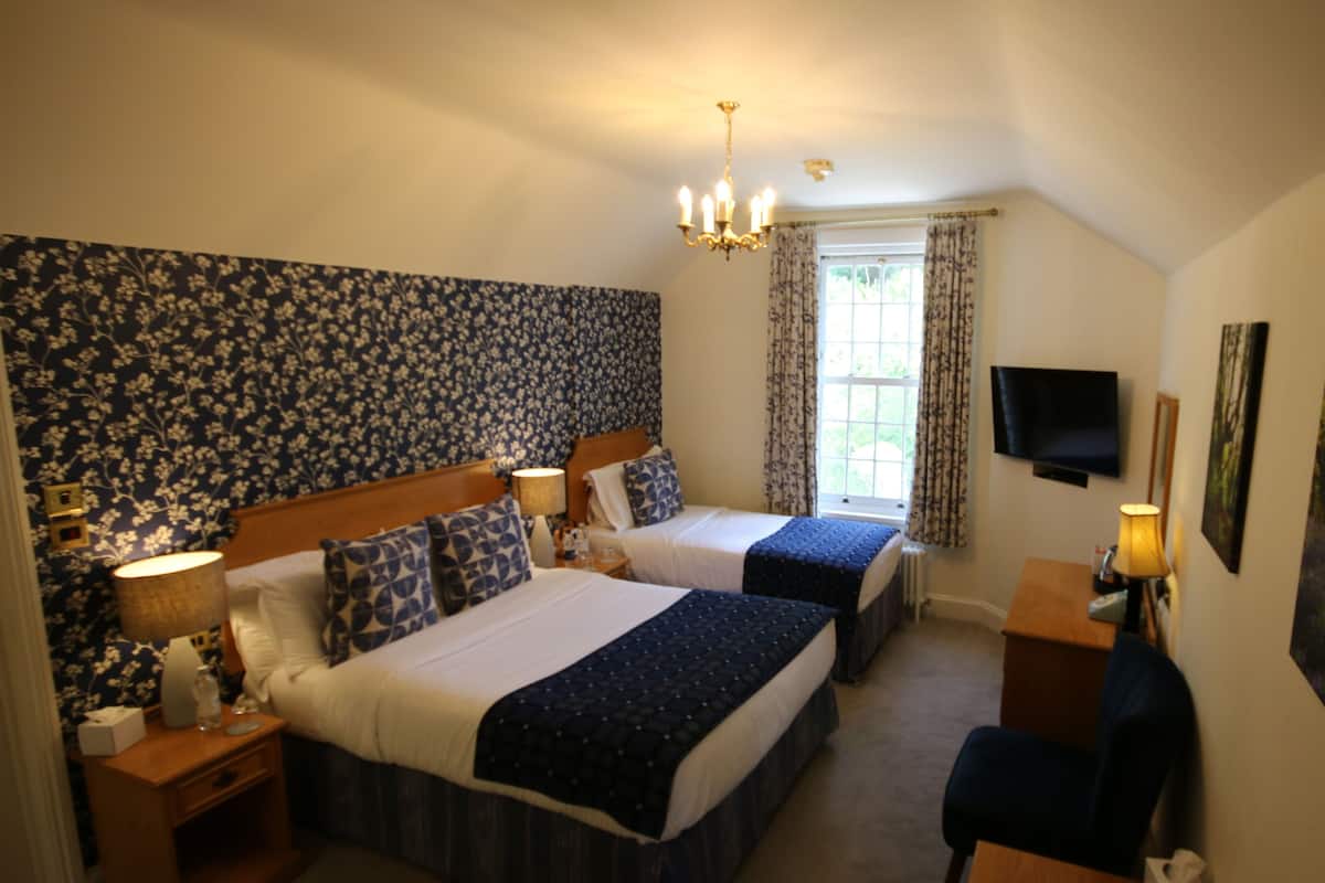 Une chambre d’hôtel avec deux lits, une télévision, un bureau et une fenêtre avec des rideaux.