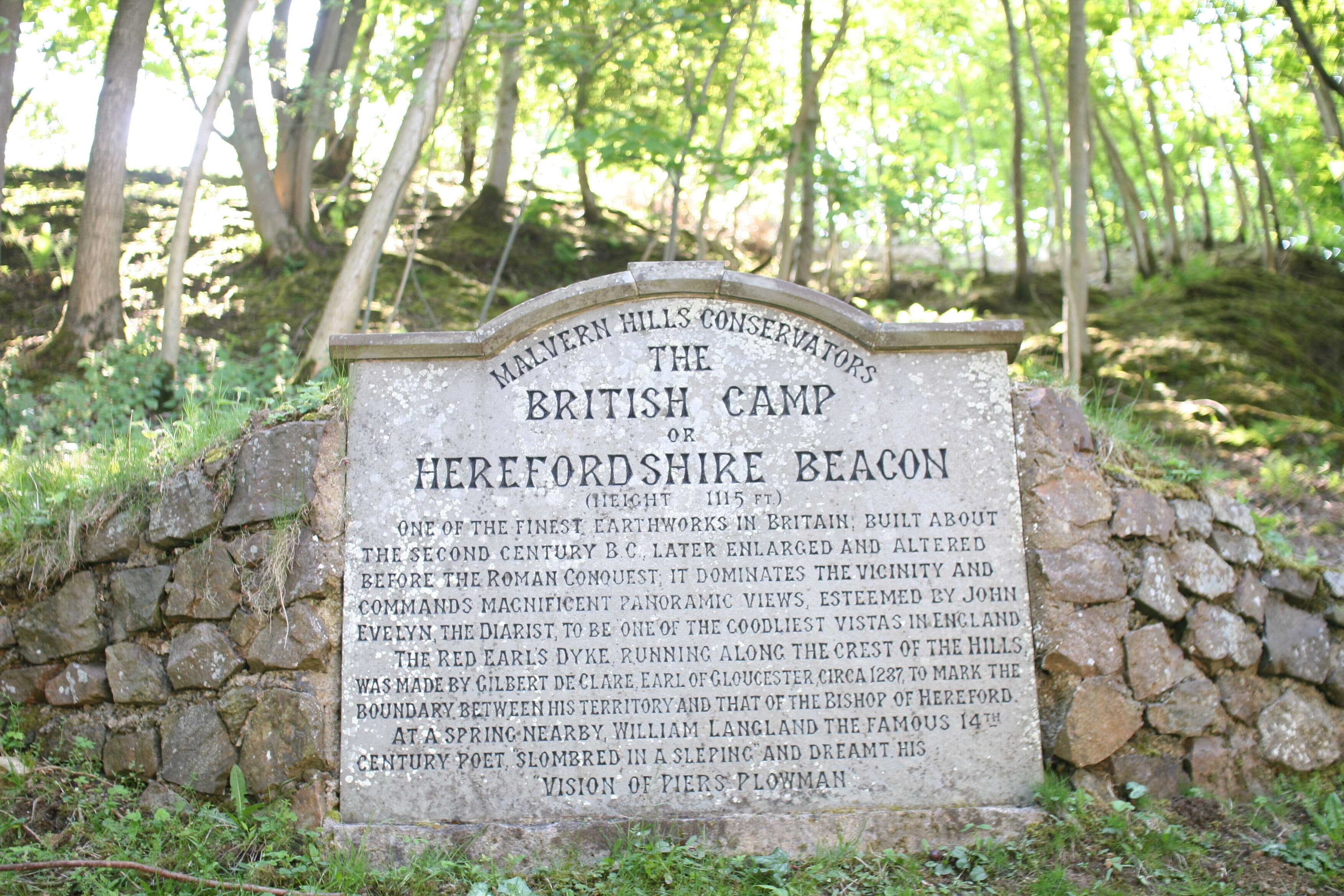 A stone sign with historical information about Malvern Hills Conservators' The British Camp or Herefordshire Beacon, including its height and significance.