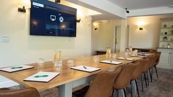 A conference room with a long table, brown leather chairs, and a large screen displaying a login screen.
