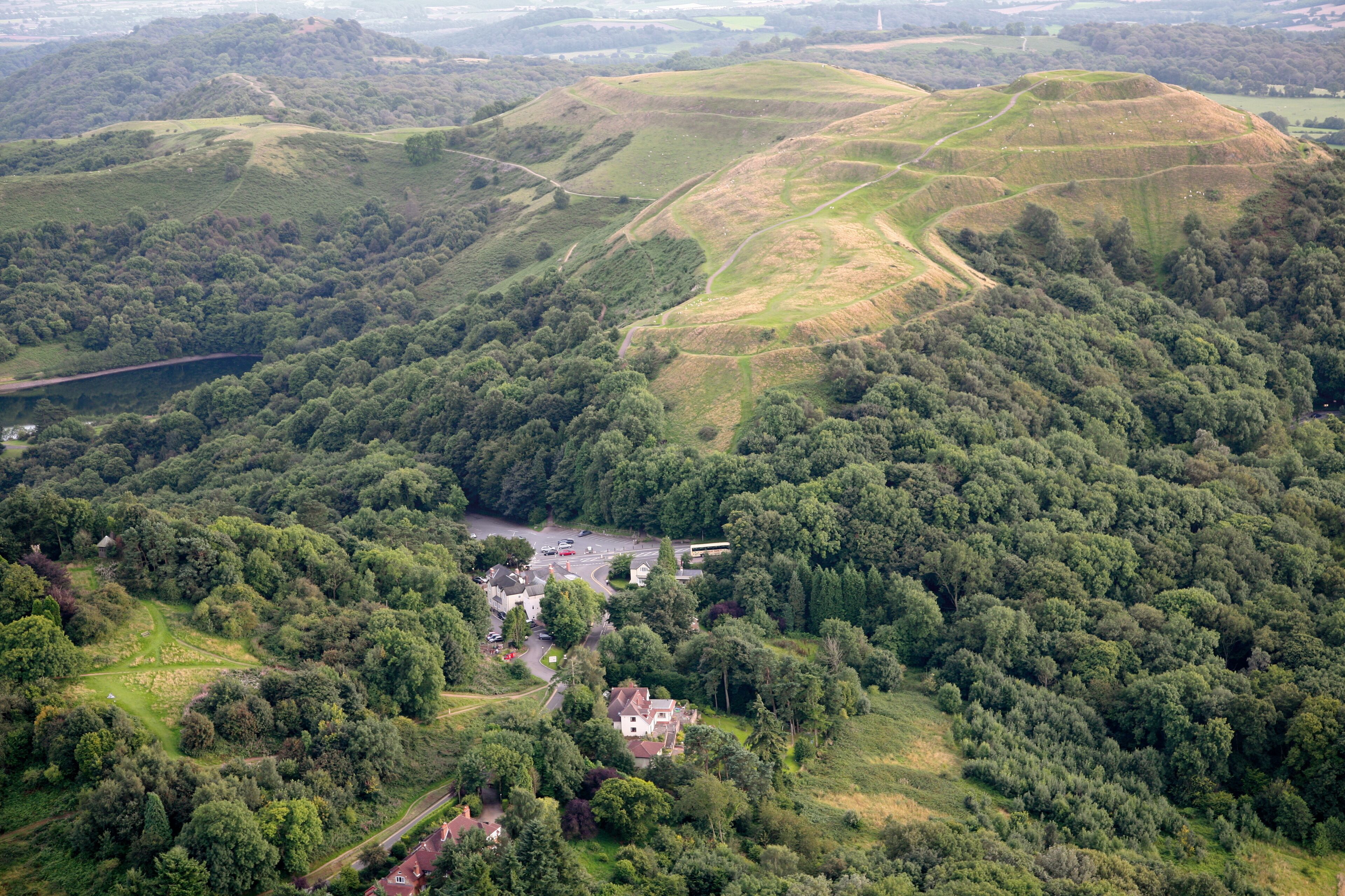 An aerial view of a rural landscape with rolling hills, a river, and scattered houses.