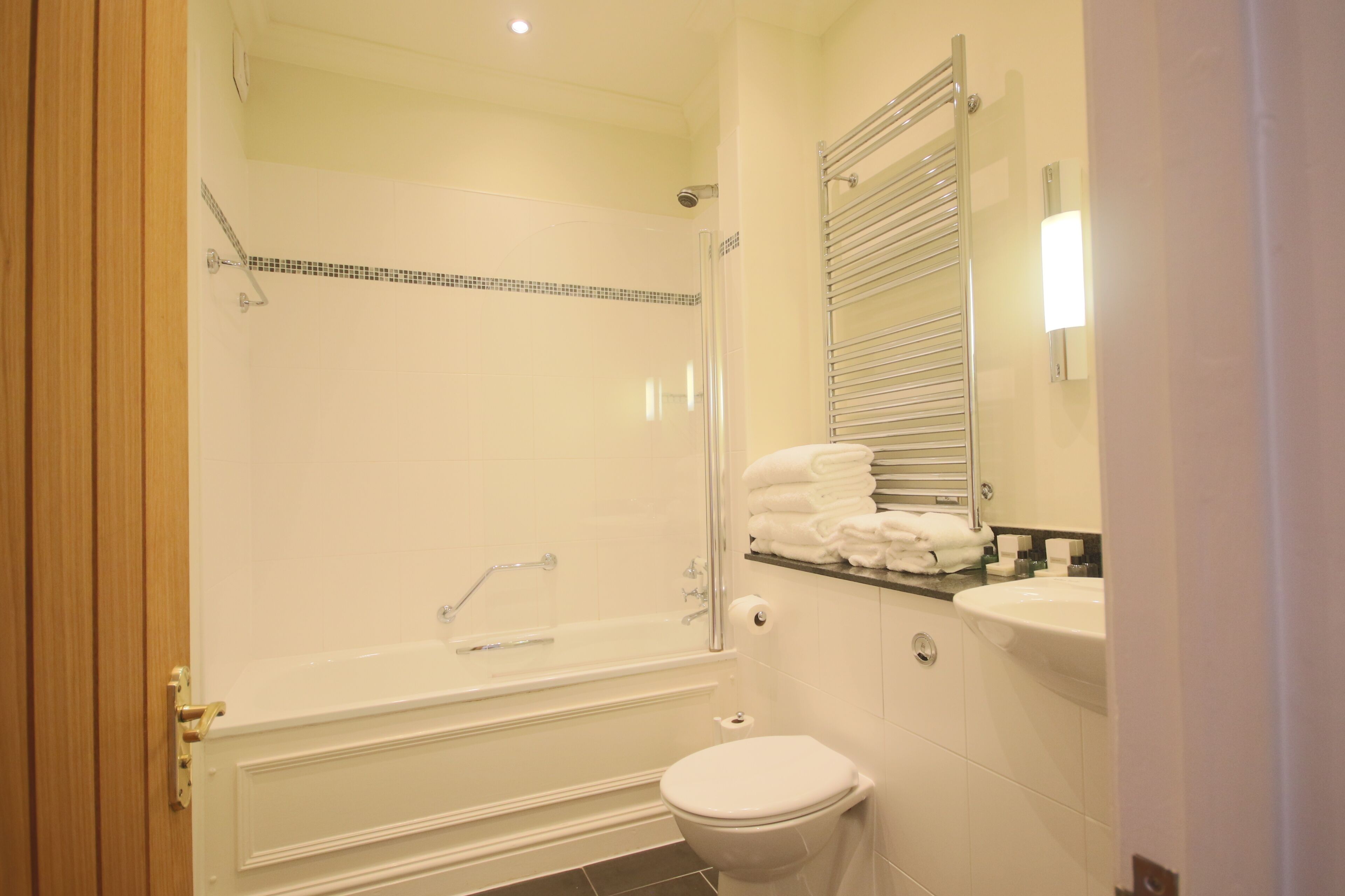A bathroom with a bathtub, toilet, and a glass-enclosed shower area.