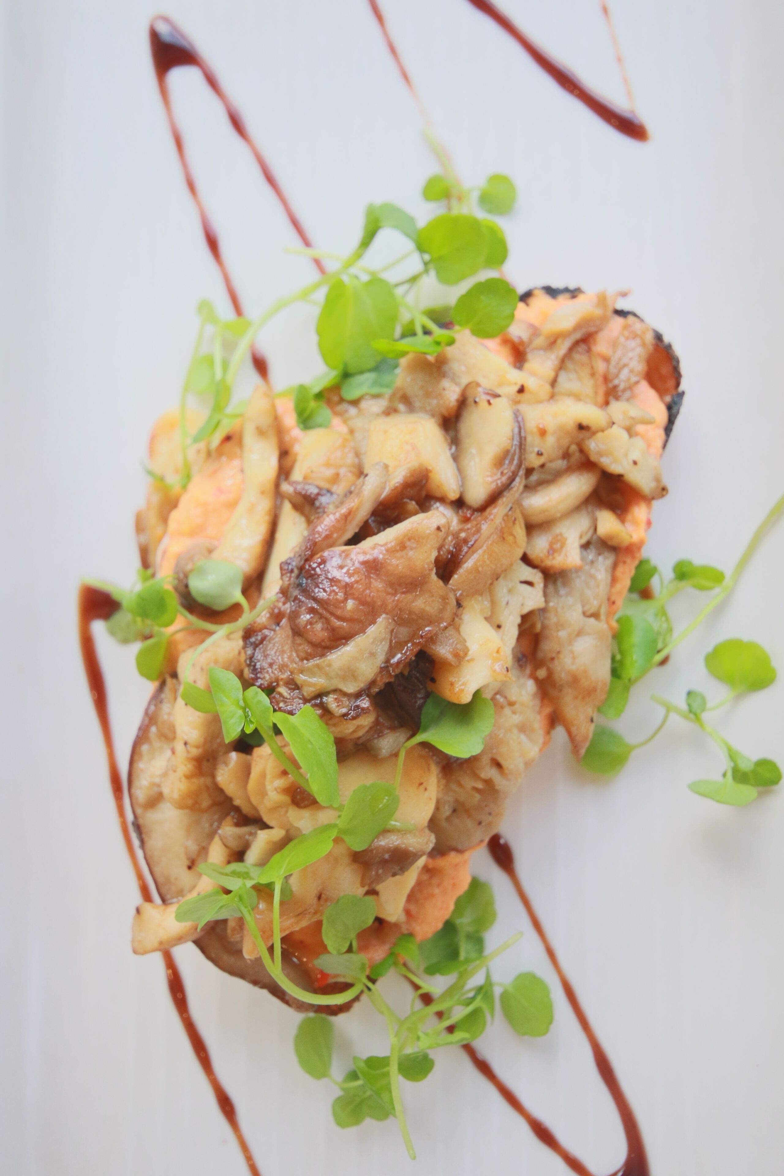 A dish with mushrooms and greens on a white plate.
