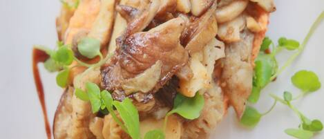 A dish with mushrooms and greens on a white plate.