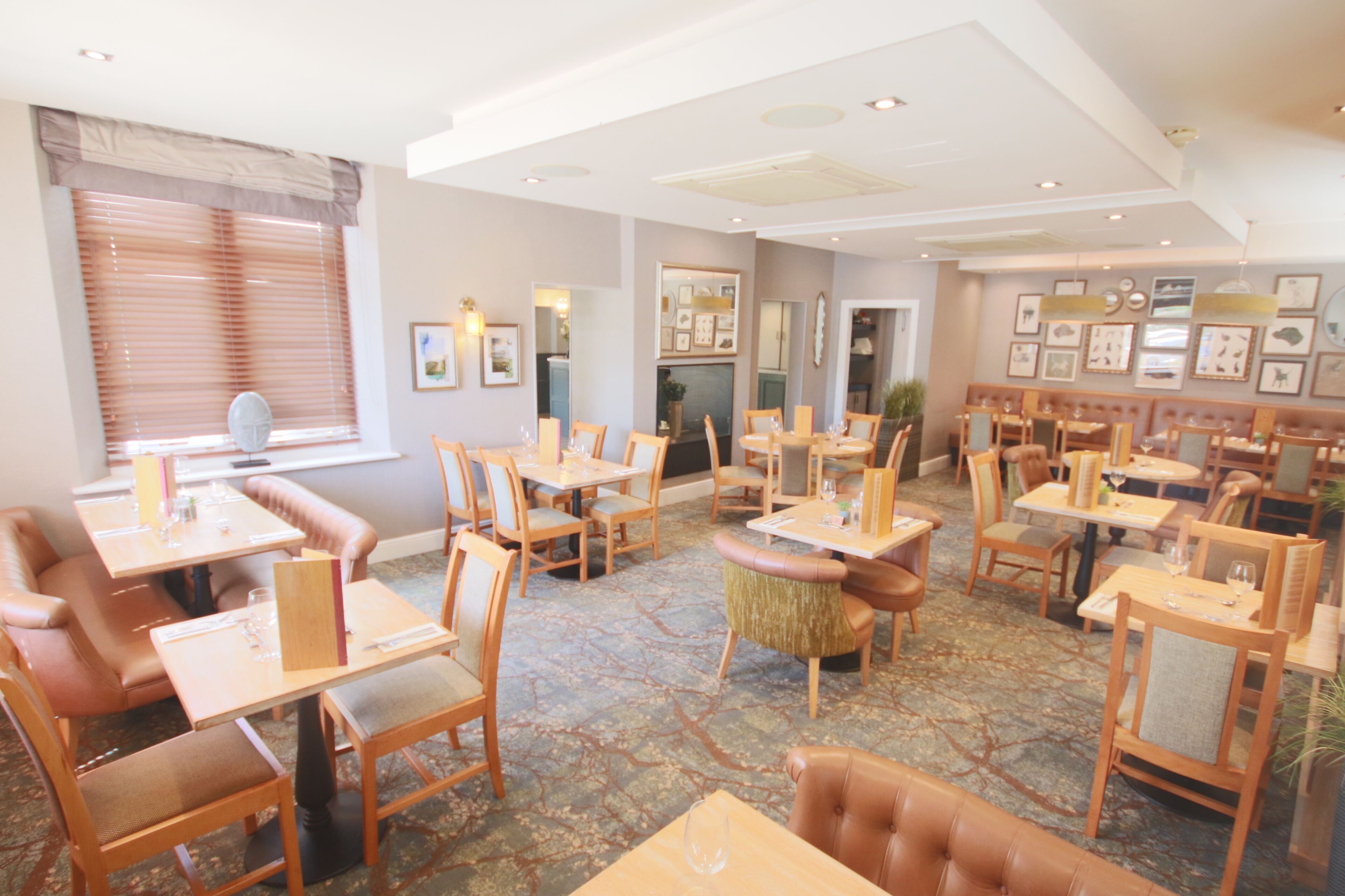 A restaurant with multiple dining tables and booths, arranged in a spacious layout with a patterned floor.