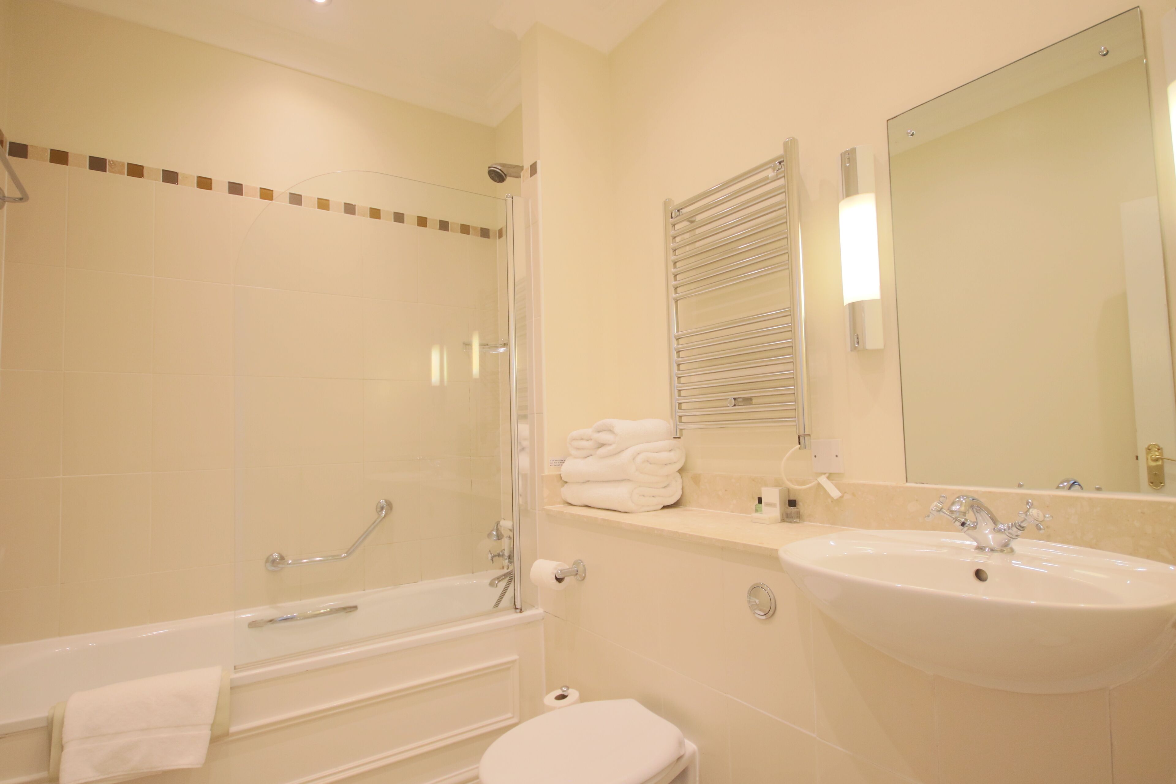 A bathroom with a bathtub, toilet, sink, and a large mirror.