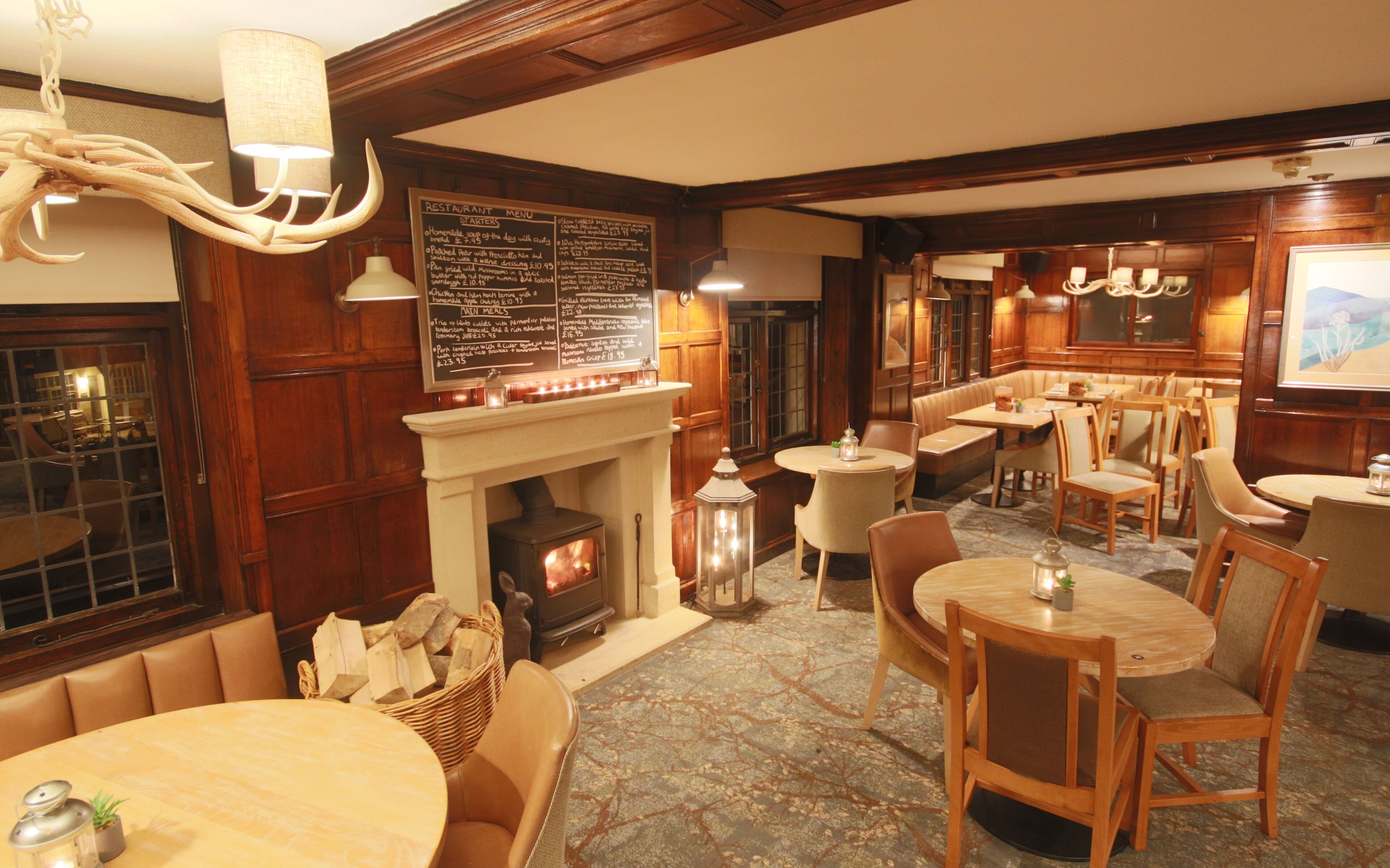 A restaurant with a fireplace, wooden furniture, and a menu board.