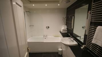 A modern bathroom with a bathtub, sink, and a large mirror.