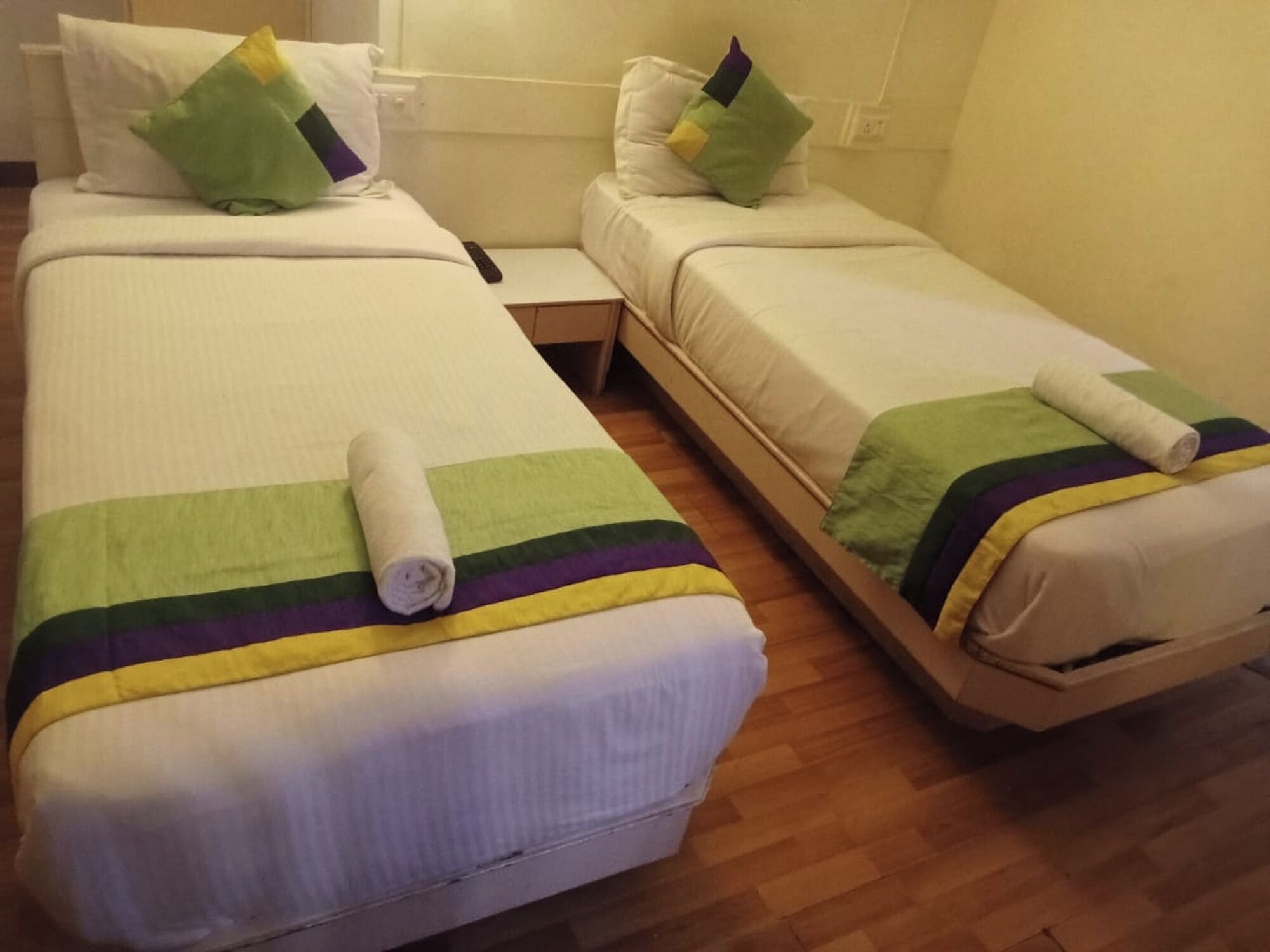 A hotel room with two single beds, each with a pillow and a blanket.