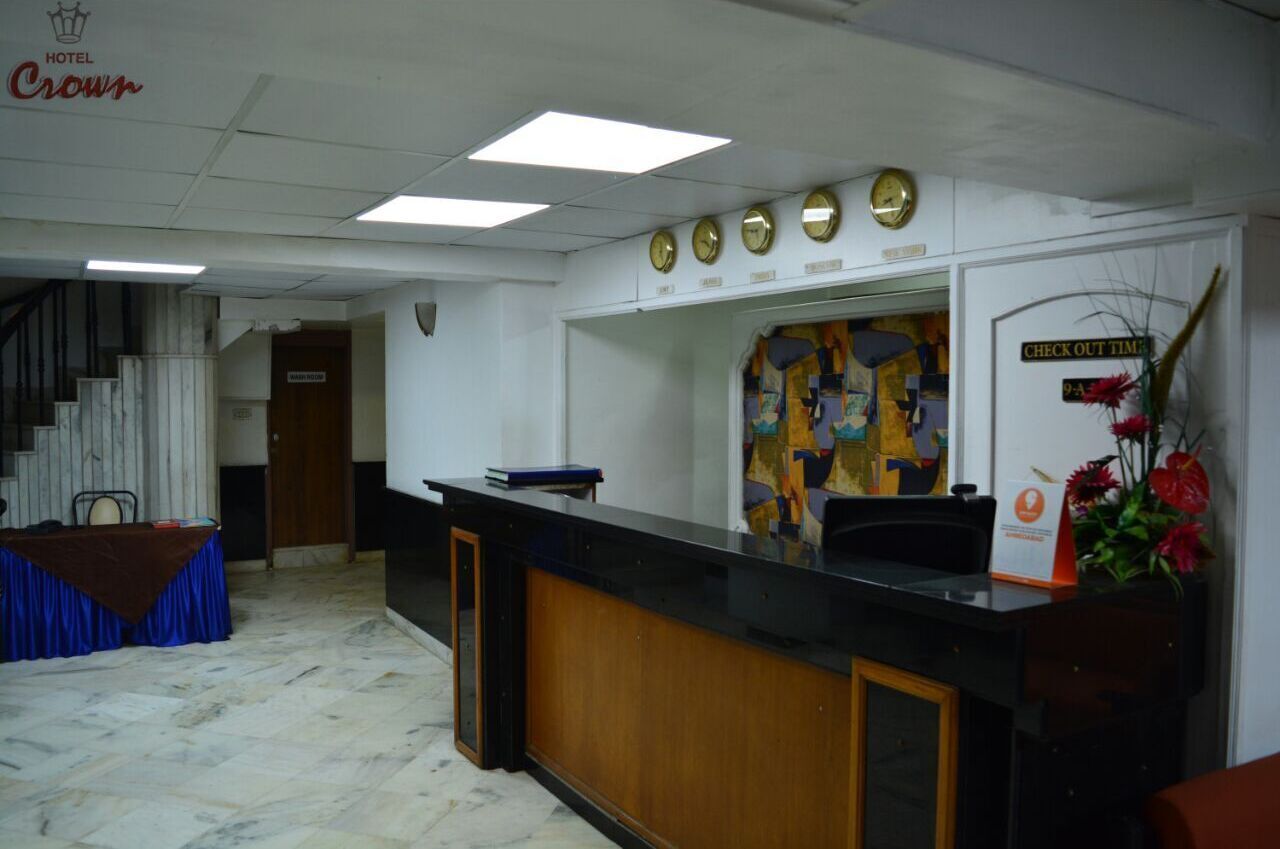 A hotel reception area with a reception desk, a clock, and a sign indicating check-out time.