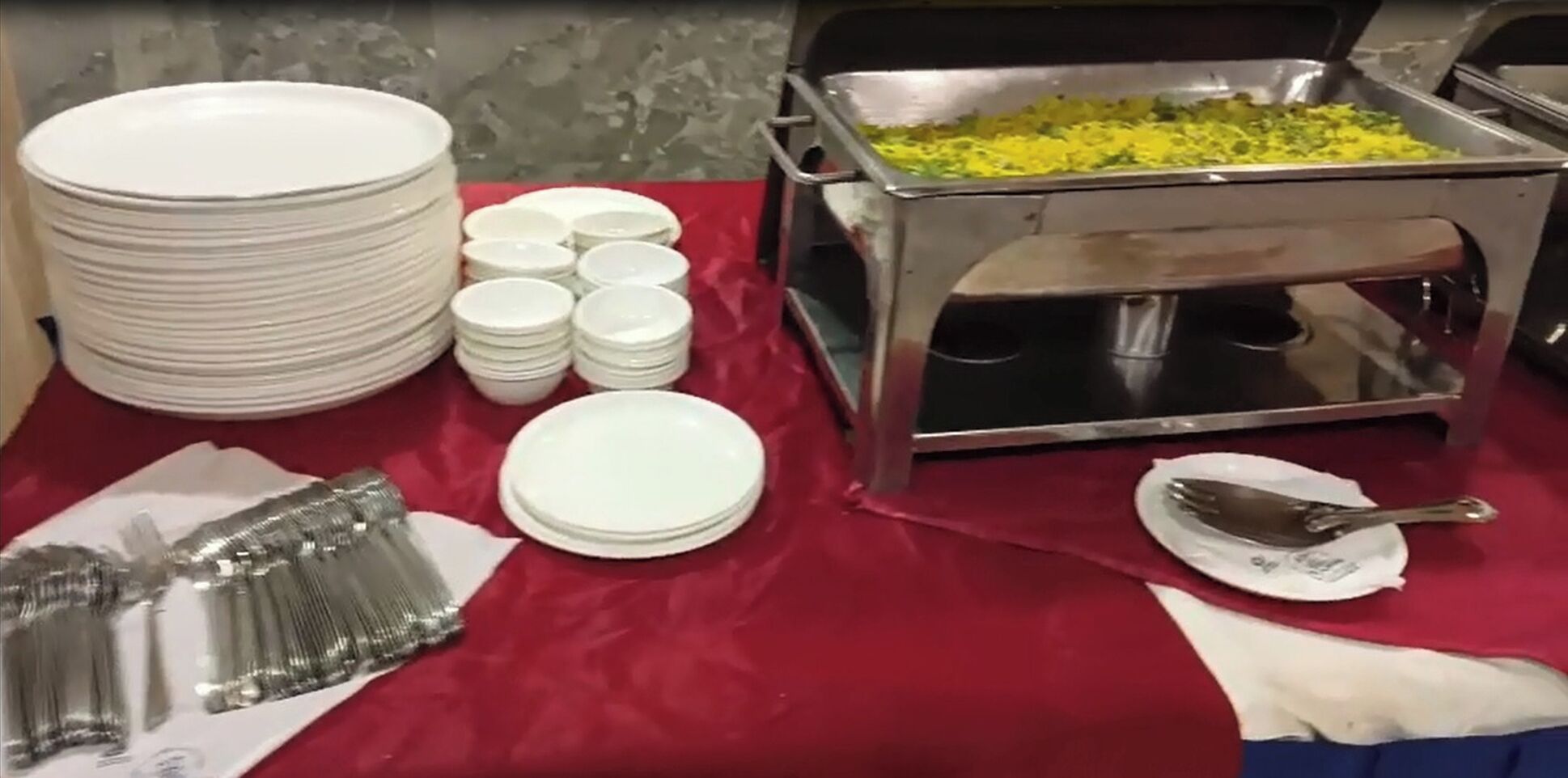 A buffet setup with stacked plates, bowls, and a serving station.