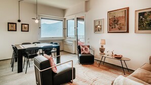Ein modernes Wohnzimmer mit Essbereich, großen Fenstern und Kunstwerken an den Wänden.