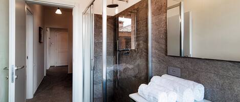 A modern bathroom with a glass-enclosed shower, a white sink with a green cabinet, and a mirror above the sink.