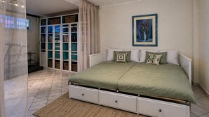 Un dormitorio con cama, ventana, puerta y un cuadro colgado en la pared.