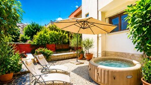 Un patio al aire libre con sillones de descanso, una bañera de hidromasaje y plantas en macetas.