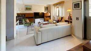 Un salón espacioso con un sofá grande, televisión y un comedor con mesa y sillas.