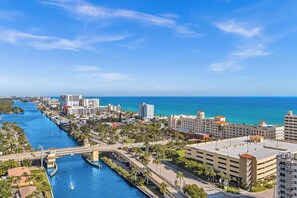 A coastal cityscape with a river, high-rise buildings, and a clear blue sky.