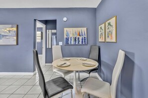 A dining area with a round table, four chairs, and artwork on the walls.
