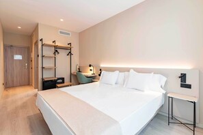 A modern hotel room with a large bed, bedside tables, a desk with a chair, and a wardrobe with a mirror. - HQ Arena Hotel (Valencia)