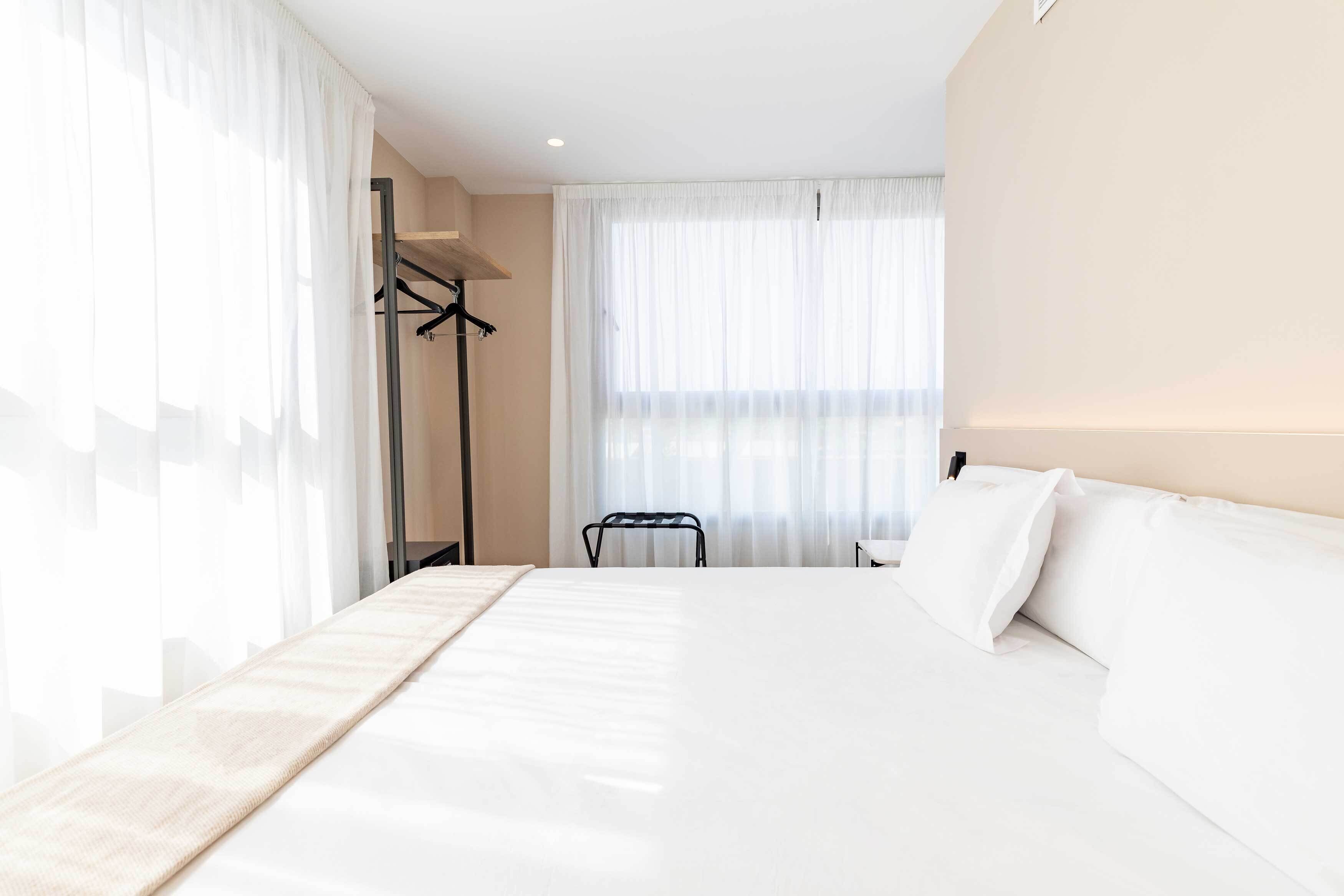 Una habitación de hotel moderna con una cama grande, una zona de estar y un armario.