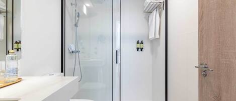 A modern bathroom with a glass-enclosed shower, a white sink, and a wooden vanity.
