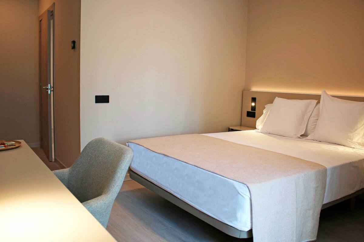 A hotel room with a bed, a desk, and a chair.