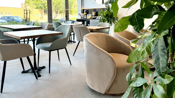 En moderne café med store vinduer, behagelige siddepladser og udsigt til gaden.
