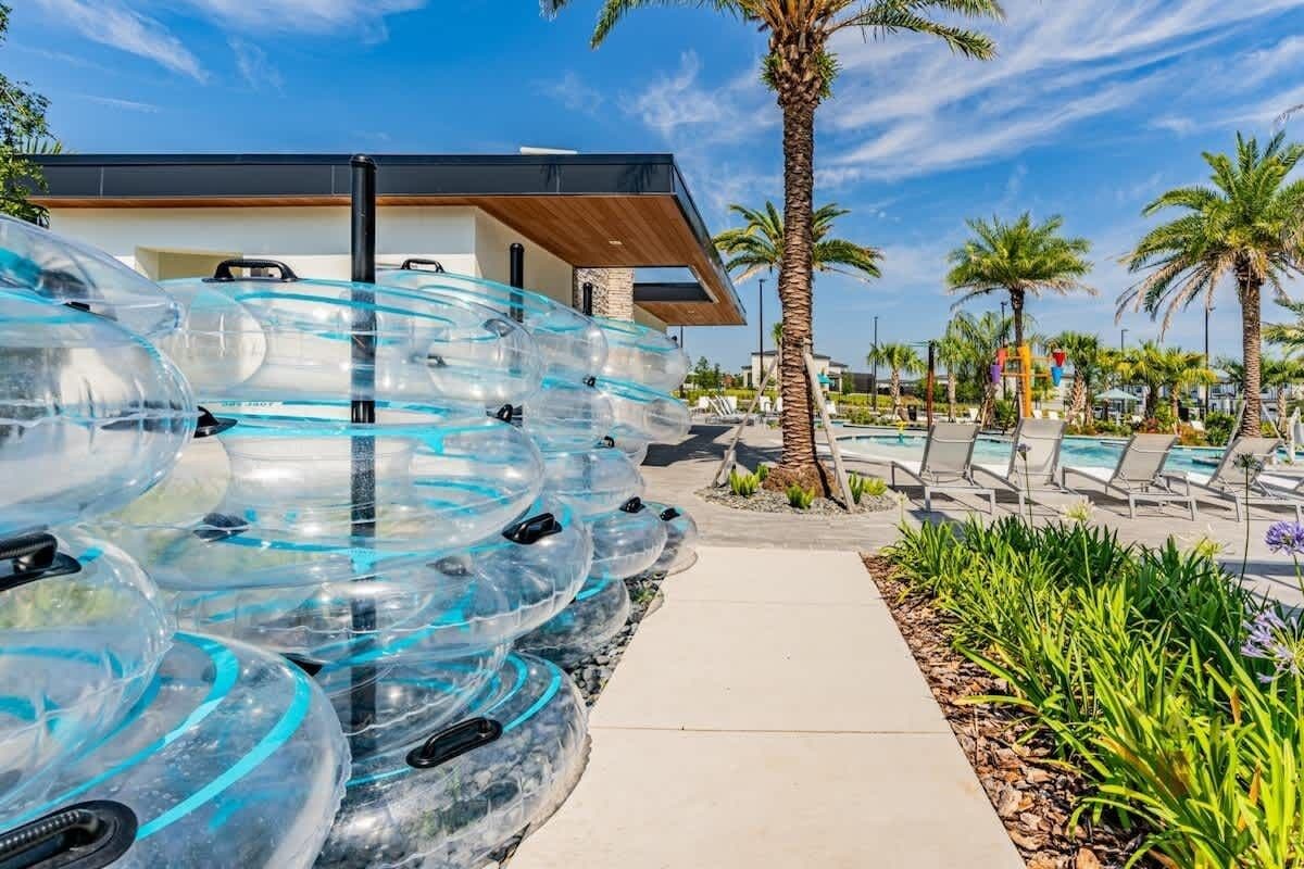 A modern building with a pool area, clear water slides, and palm trees.