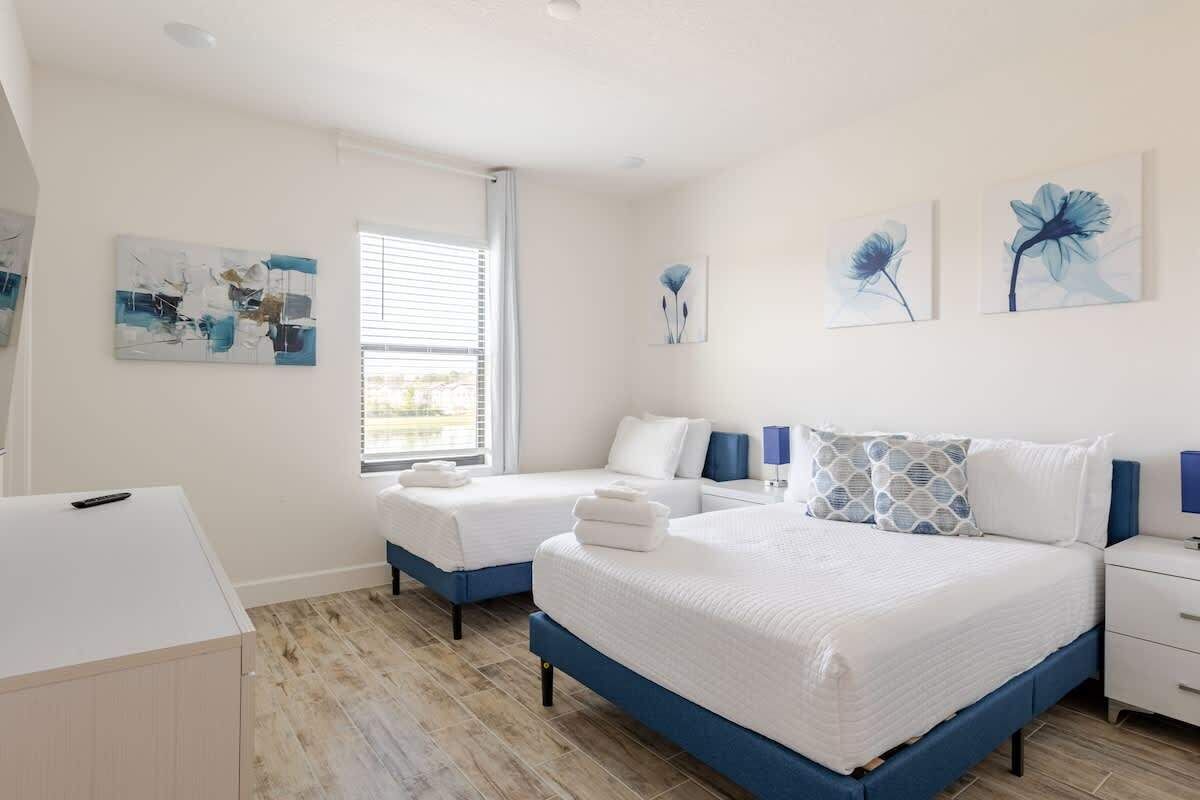 A bedroom with two beds, a desk, and artwork on the walls.