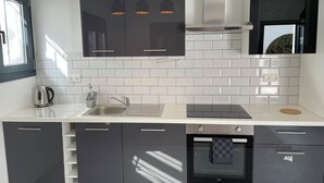 A modern kitchen with black cabinets, a stainless steel sink, and a built-in oven. - Superior 2-Bedroom boutique apartment with Stunning Views & Modern Amenities (Cómpeta)