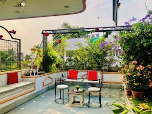 Une terrasse sur le toit, aménagée avec un espace salon, des plantes en pot et offrant une vue sur les bâtiments environnants.