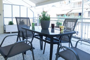 A balcony with a round table, four chairs, a potted plant, and a mug. - Modern 1 Bd Balcony Apt in Kato Patisia (Athens)