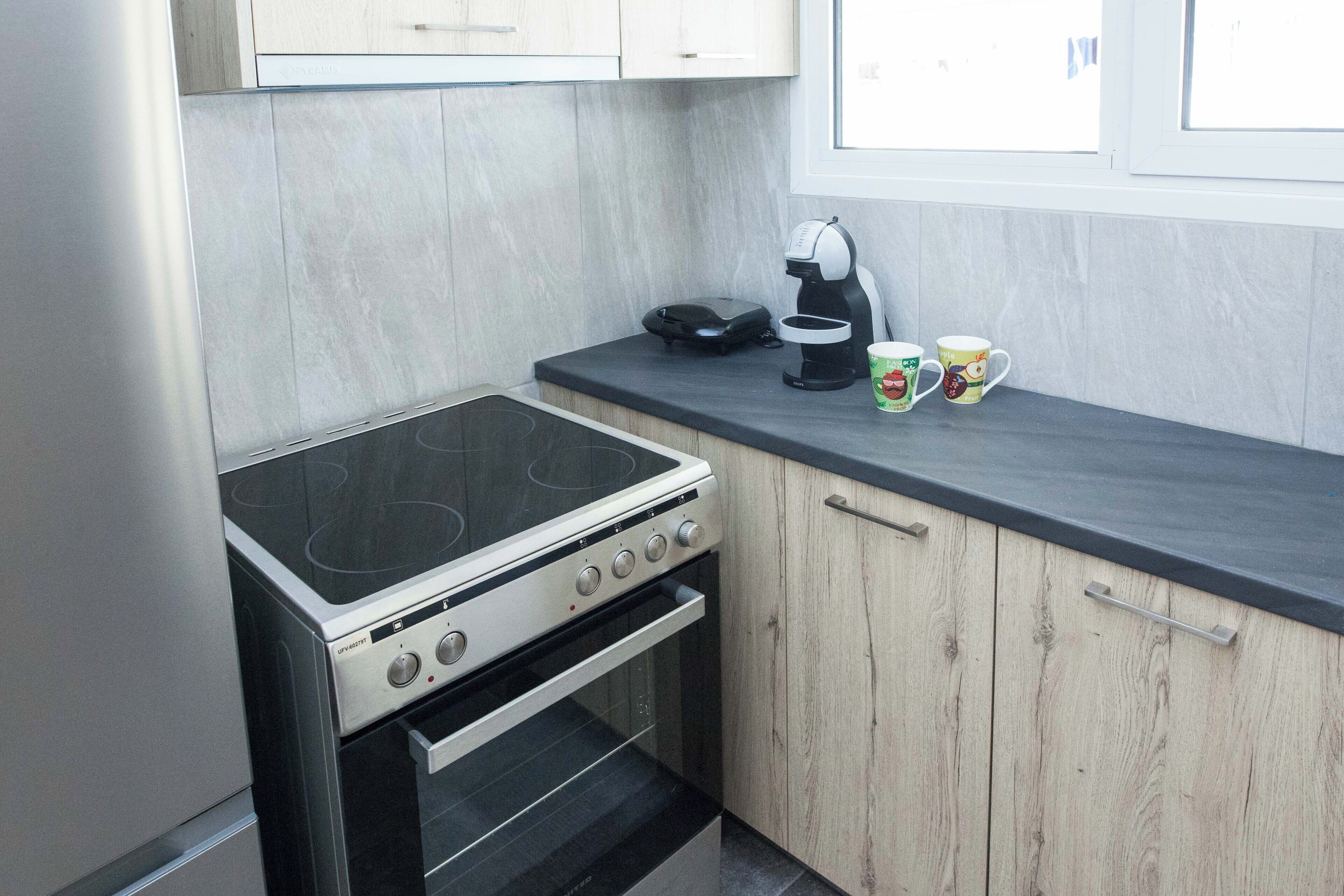 A compact kitchen with a stove, oven, and a coffee maker on the countertop.
