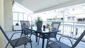 A balcony with a table and chairs, a potted plant, and a view of the surrounding buildings. - Modern 1 Bd Balcony Apt in Kato Patisia (Athens)