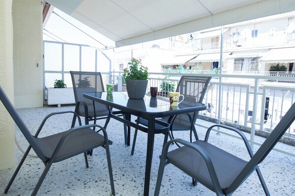 A balcony with a table and chairs, a potted plant, and a view of the surrounding buildings. - Modern 1 Bd Balcony Apt in Kato Patisia (Athens)