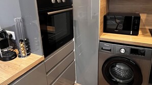 Une cuisine compacte équipée d’un four, d’un micro-ondes et d’un lave-linge intégrés.