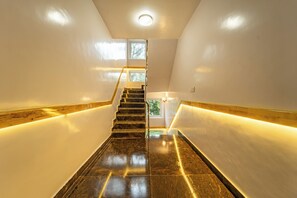 A modern interior with a staircase, polished stone flooring, and warm lighting. - THE SUITES (Anekal)