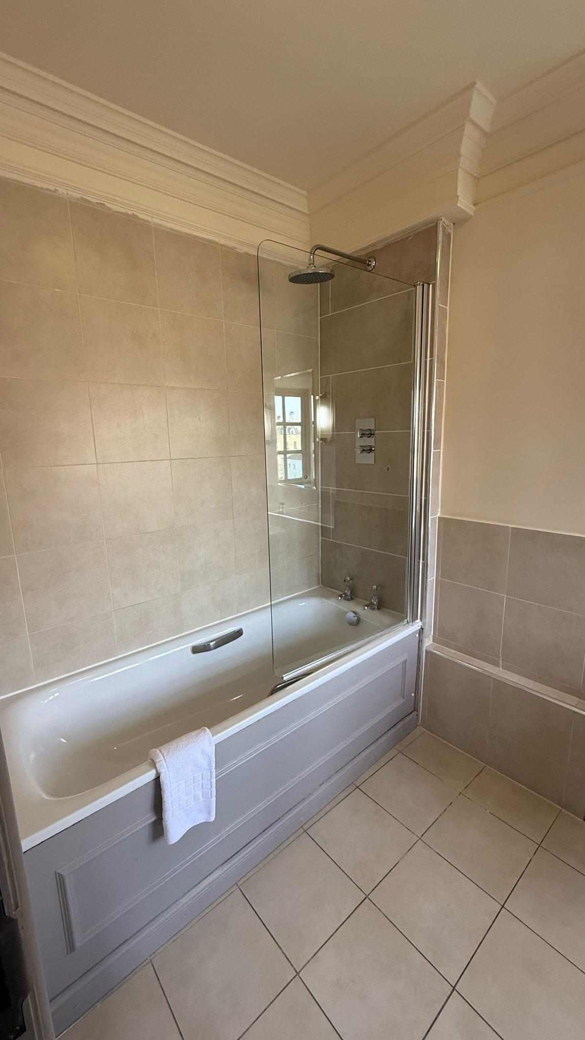A modern bathroom with a glass-enclosed shower, a large bathtub, and beige tiles.