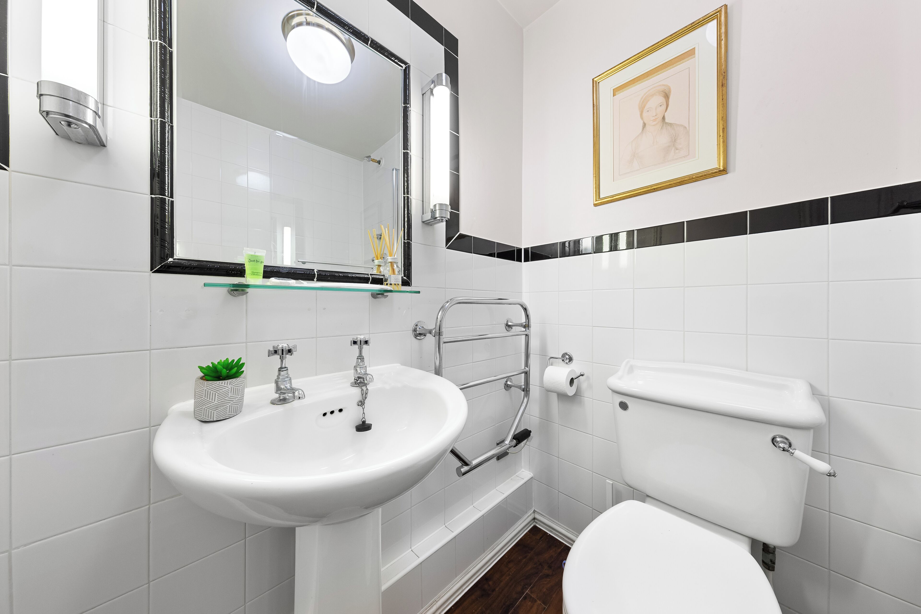 A modern bathroom with a white sink, mirror, and toilet.