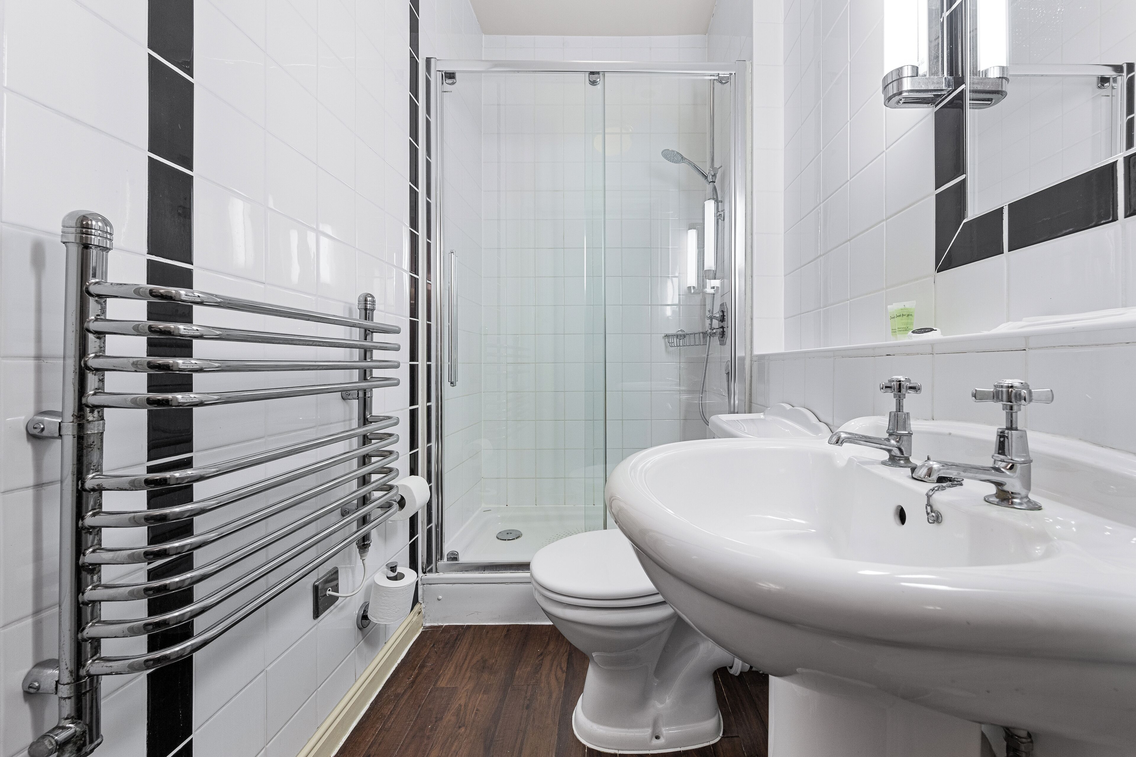 A modern bathroom with a glass shower enclosure, a white toilet, and a large sink with a mirror above it.