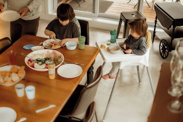 Un comedor con una mesa de madera, platos de comida y un cochecito de bebé al fondo.