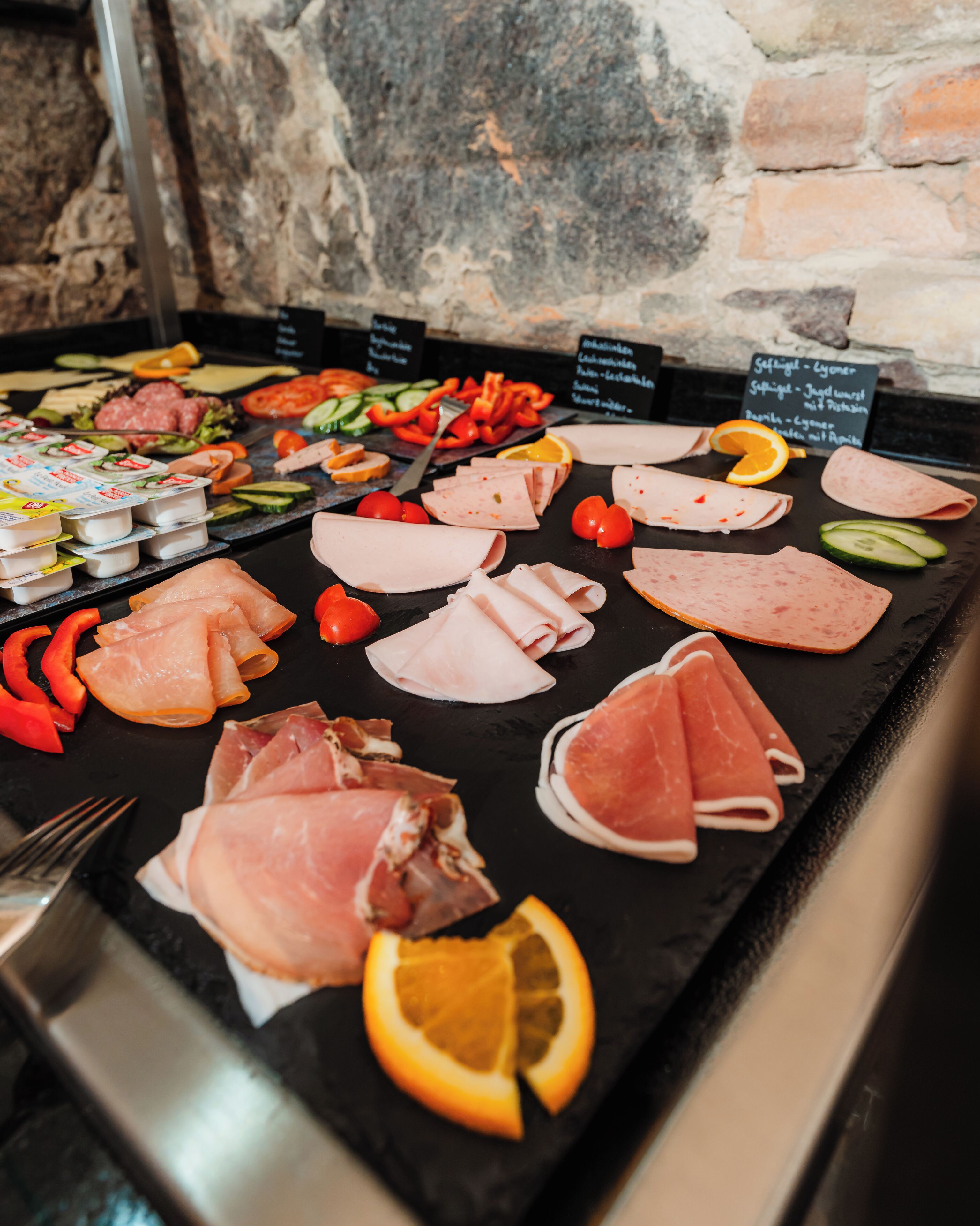 A charcuterie board with various meats, cheeses, and fruits.